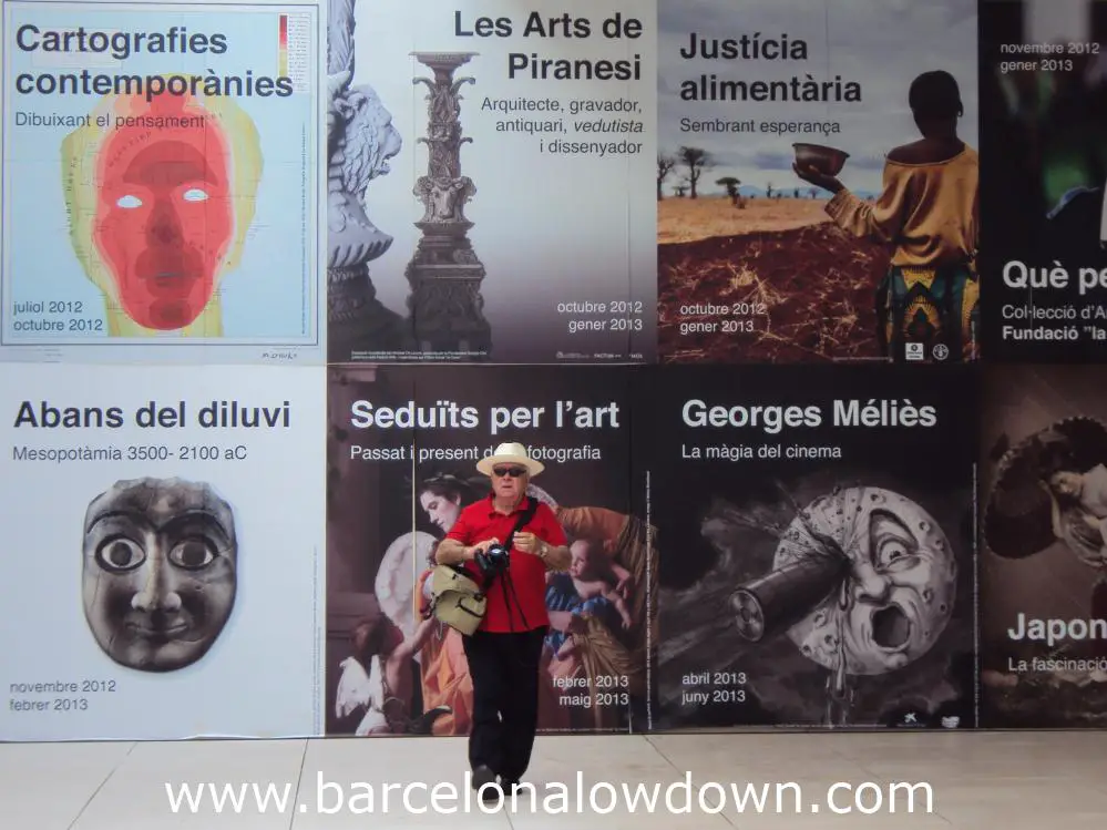 A tourist in a straw hat in front of posters advertising future exhibitions at Caixa Forum