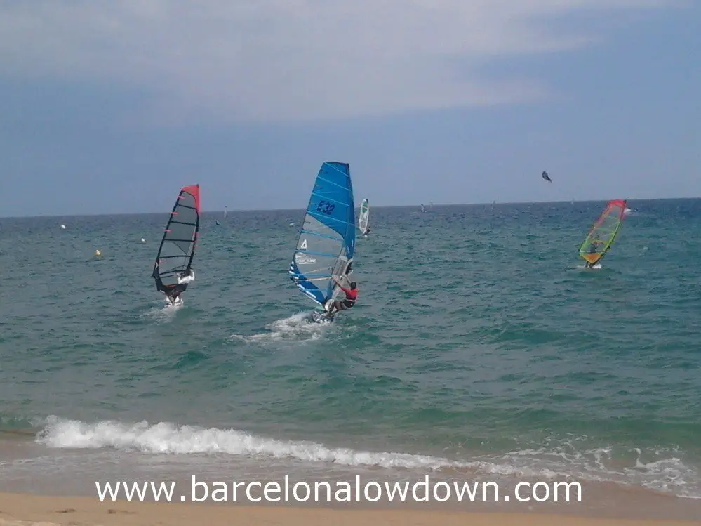 3 windsurfers and a kiesurfer sailing at Badalona beach near Barcelona