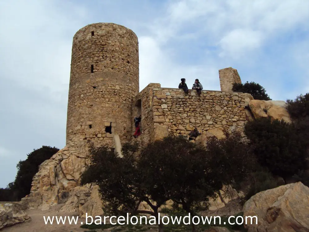 2 walkers taking a rest on the stone walls of Burriac castle