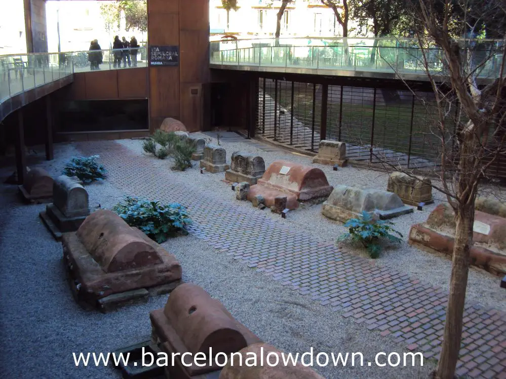 A group of tourists looking down on the ancient Roman graveyard at the MUHBA Via Sepulcral Romana Barcelona
