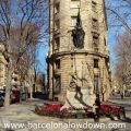 Statue of Rafael Casanova in the Eixample district of Barceona, The statue is surrounded by trees and elegant old buildings.
