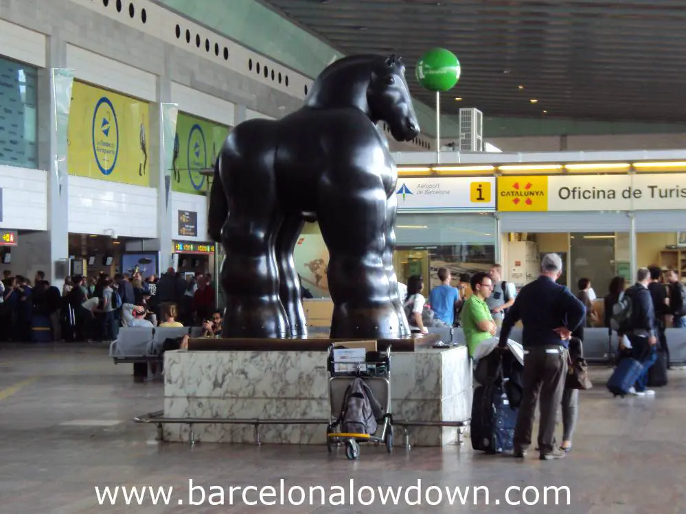 3 bored tourists waiting by Botero's black horse statue in Barcelona Airport