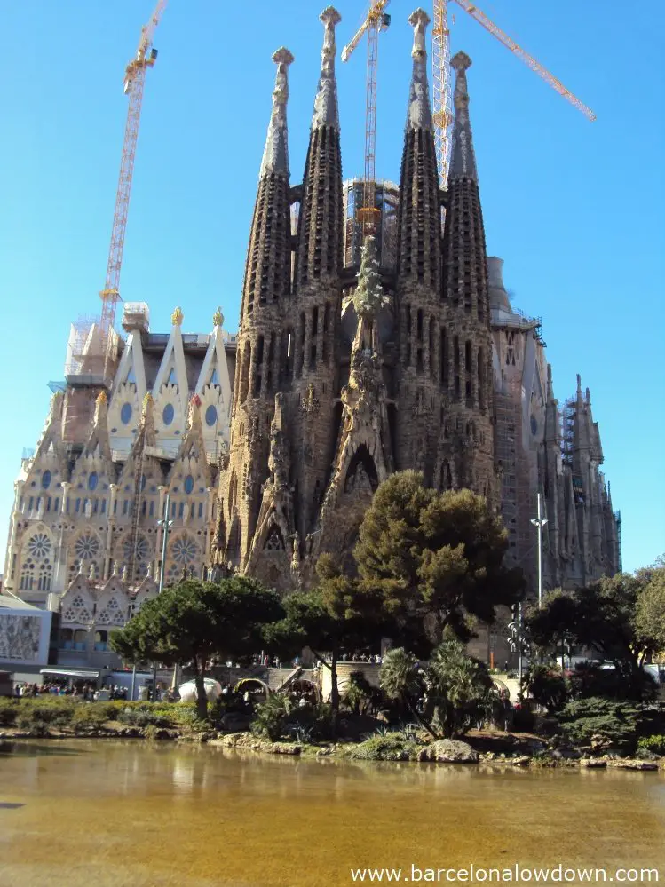 The Nativity Scene Façade of the Sagrada Familia church with a small lake in the foreground, Barcelona