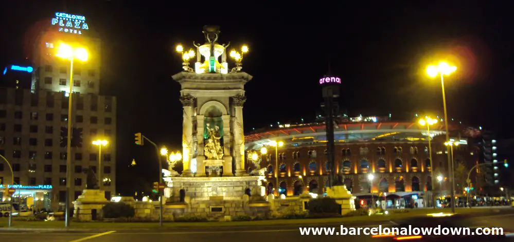Plaça d'Espanya Barcelona at night. The neoclasical fountain floodlit with the arenys shopping centre and Catalonia Plaza hotel in the background.