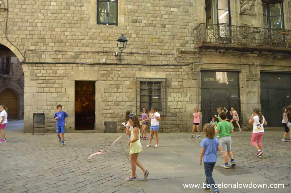 Children playing in front of the Shoe Museum in Plaça Sant Felip Neri