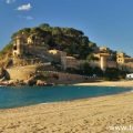 The fortified medieval town of Tossa de Mar (La Vila Vella) and the long sandy beach. A sunny day on the Costa Brava, Spain.