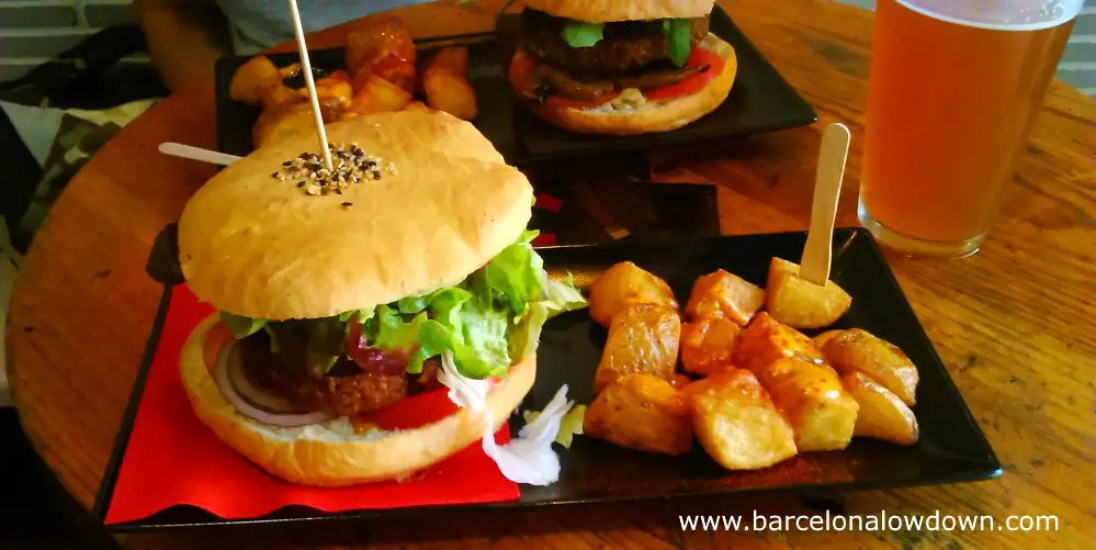 Vegan burgers in hand baked bread rolls asrved with fried potatoes and craft beer in Cat Bar Barcelona