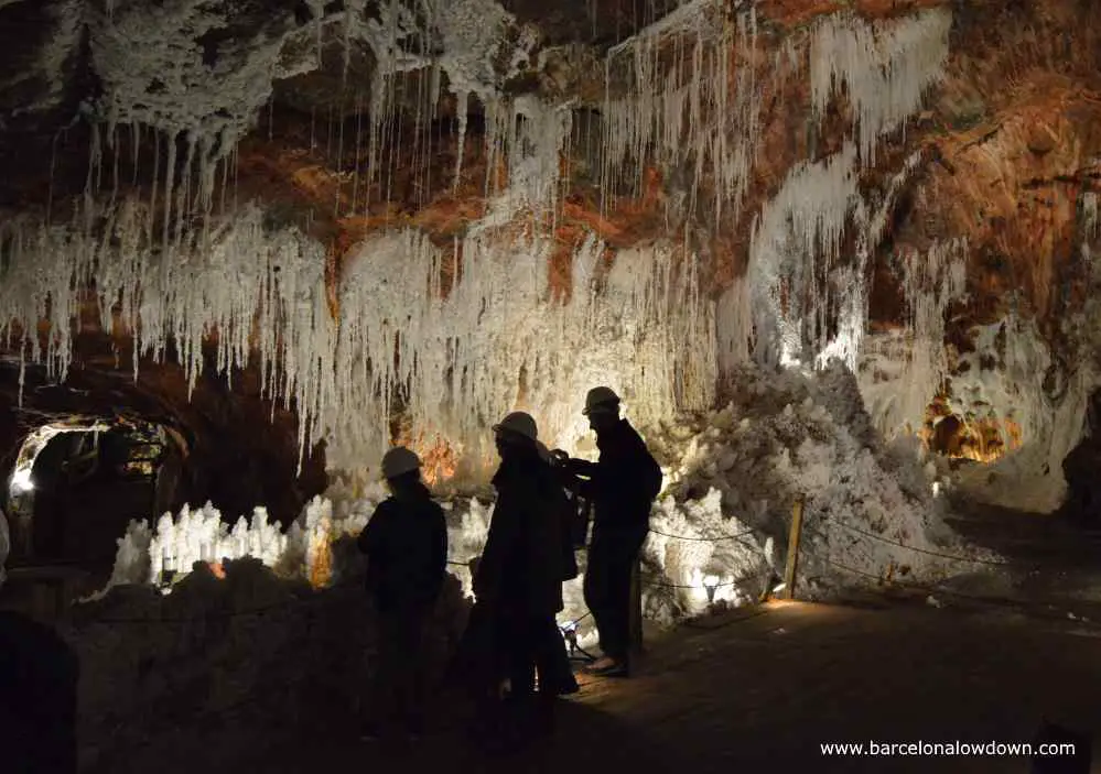 A group of tourists visiting the salt mountain mines. The visitors are silhouetted in front of the salt stalactites and stalagmites in a large chamber called the sistine chapel.