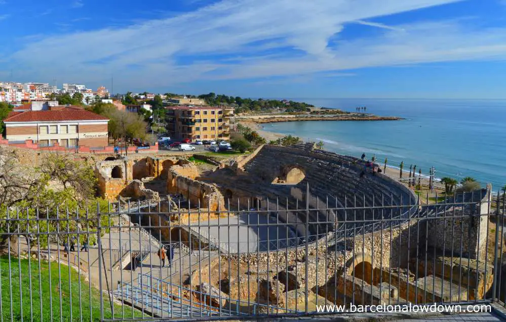 The ancient Roman amphitheatre of Tarragona with views of the beach and blue Mediterranean sea in the background