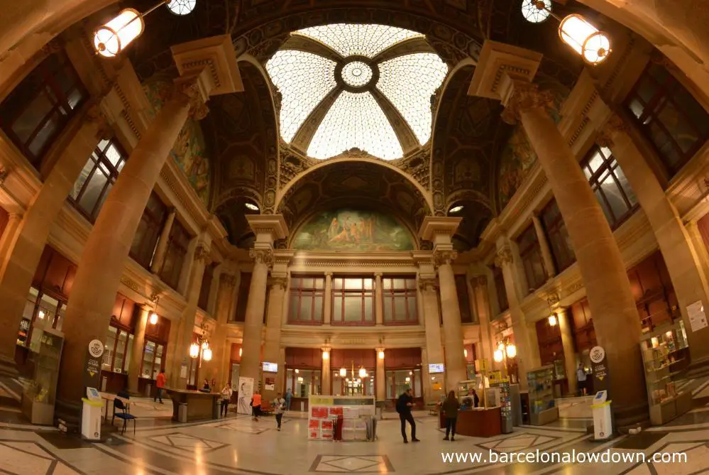 Interior view of Barcelona Post Office thru a fisheye lense. You can see the glase ceiling dome and mosaics which decorate the ceiling and upper wals. Also the slender corinthian columns whic support the roof and old fashioned interior. The photo shows the typical distortin associated with fisheye lenses.