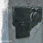 The metal plaque on the side of the monument to us servicemen in Barcelona. The design includes an eagle atop a globe and an anchor with the letters USN.