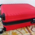 A red hand luggage size American Tourister suitcase with a built in combination lock
