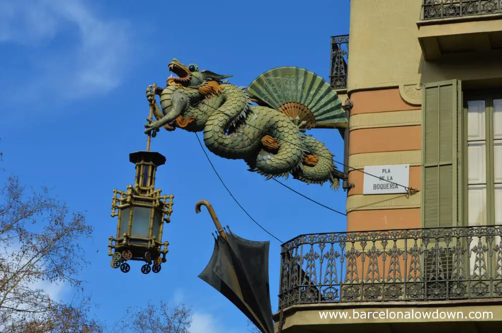 The painted steel Chinese dragon sign on the façade of the umbrella house Barcelona. The dragon is adorned by a fan, an umbrella and a bamboo lantern.