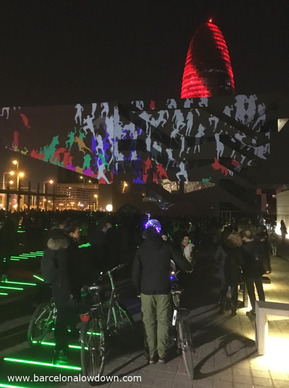 People watching the animated projections on the side of the DHUB Barcelona design museum durin Llum BCN. Barcelona festival of light.