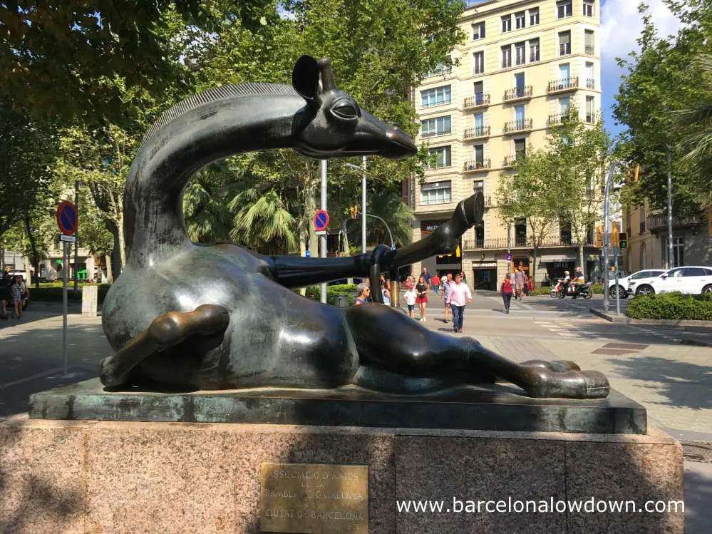 Bronxe statue of a Giraffe by Josep Granyer, the giraffe is reclining in a sexy pose, it's tail draped over one hoof