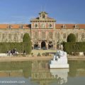 Photo of the Catalan Parliament building in Barcelona citadel park. Ther is a small pond in front of the building with a white marble statue of a crying girl.