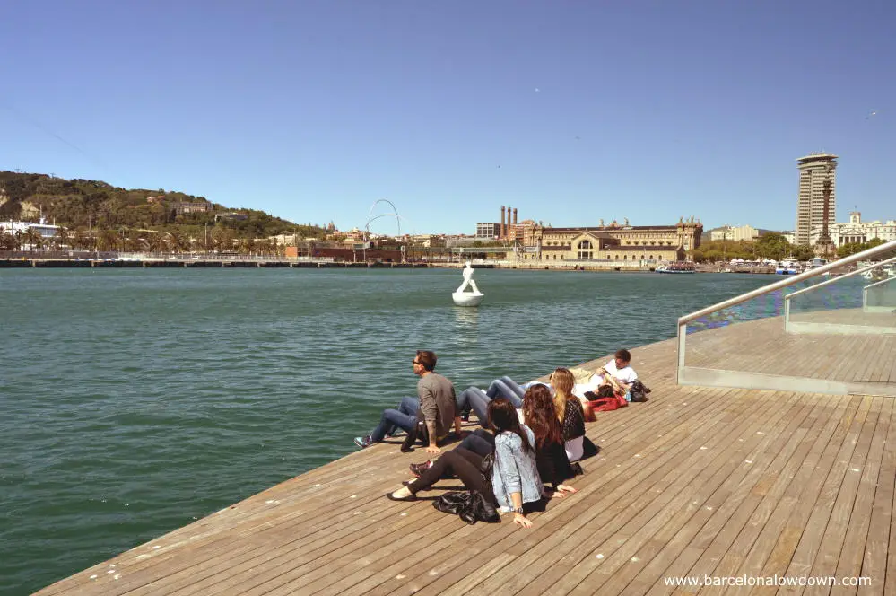 Tourists sitting on the Rambla del Mar boardwalk in Barcelona Harbour