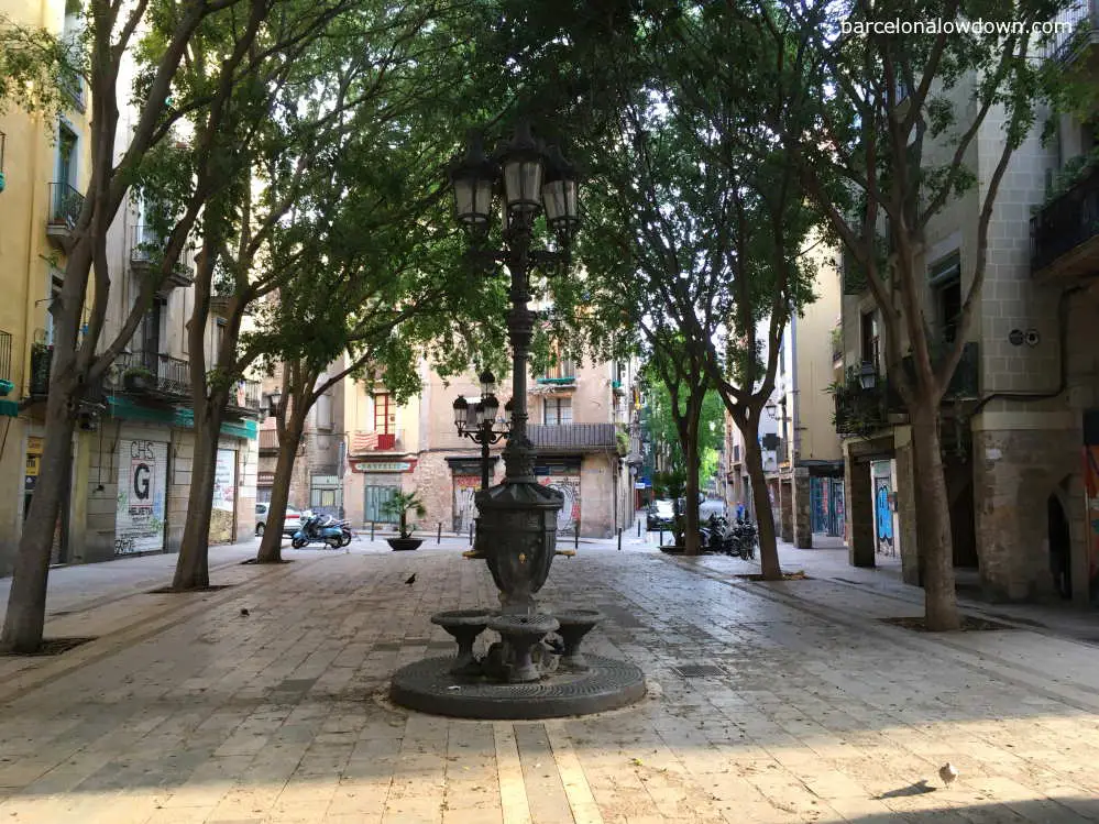 A pretty tree lined plaza with a cast iron water fountain in Barcelonas el Born neighbourhood.