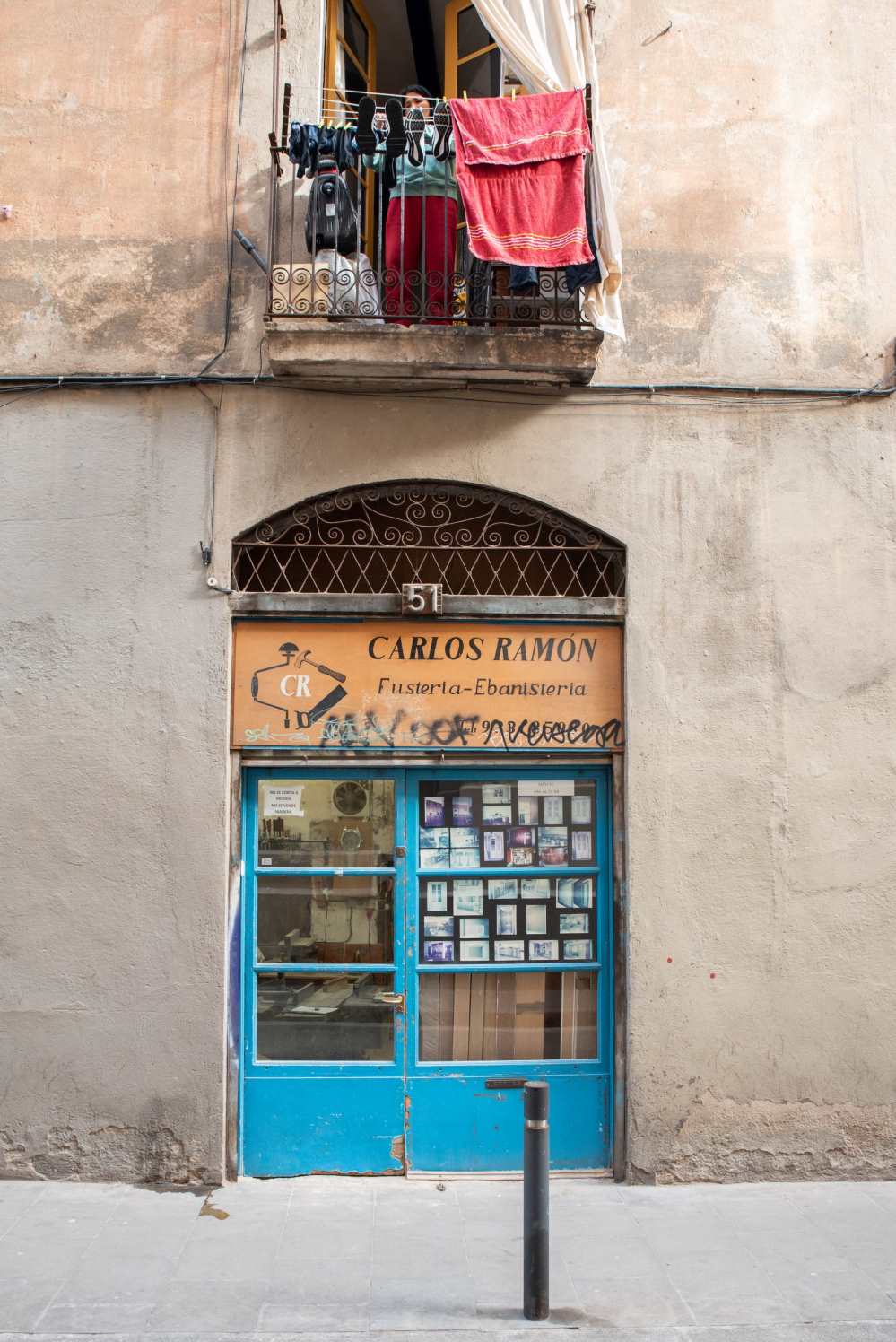 Street scene in Barcelona, a lady is hanging out washing on her balcony above a carpenter's workshop - Photo by Ben Holbrook