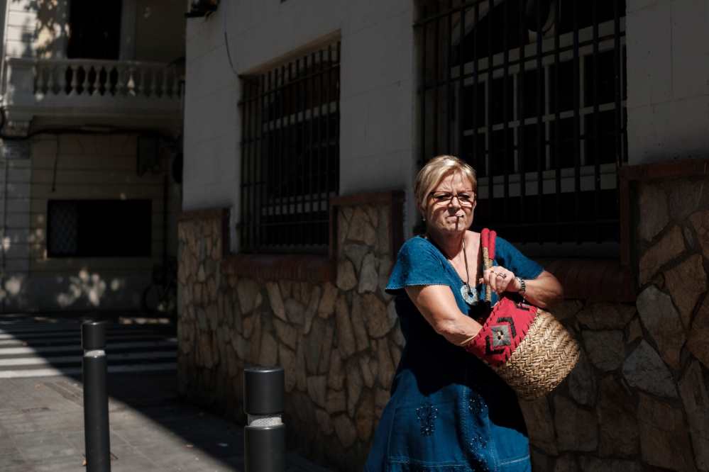 A woman in a blue dress is rummaging in her handbag looking for her lighter as she walks down a street in Barcelona - Photo by Ben Holbrook