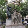 A monument in Barcelona depicting a semi nude woman holding a torch and a soviet style carving of a farmer