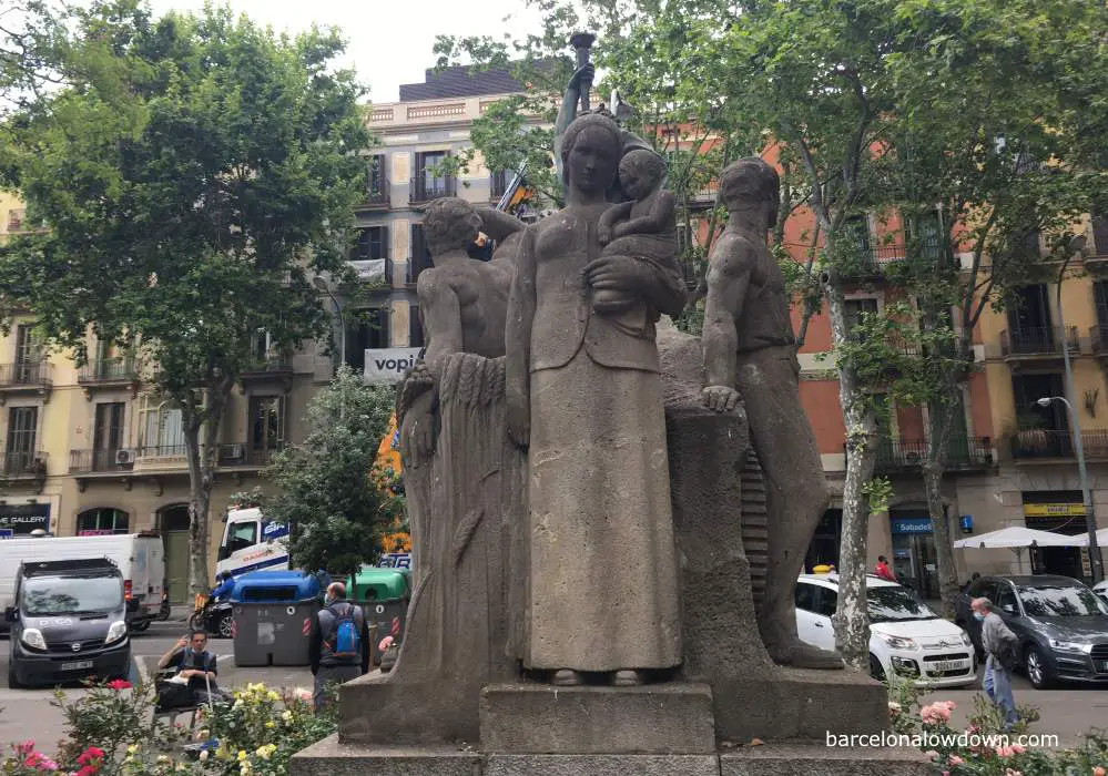 Stone monument of a woman holding a baby flanked by two workers