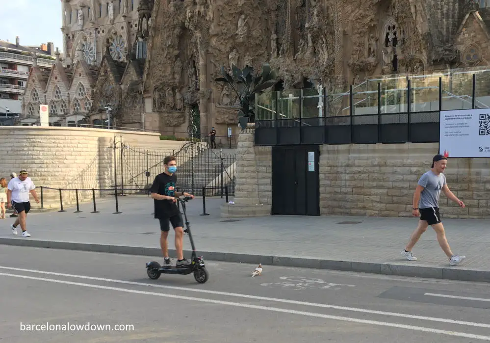 An electric scooter passing in front of the Sagrada Familia Basilica in Barcelona