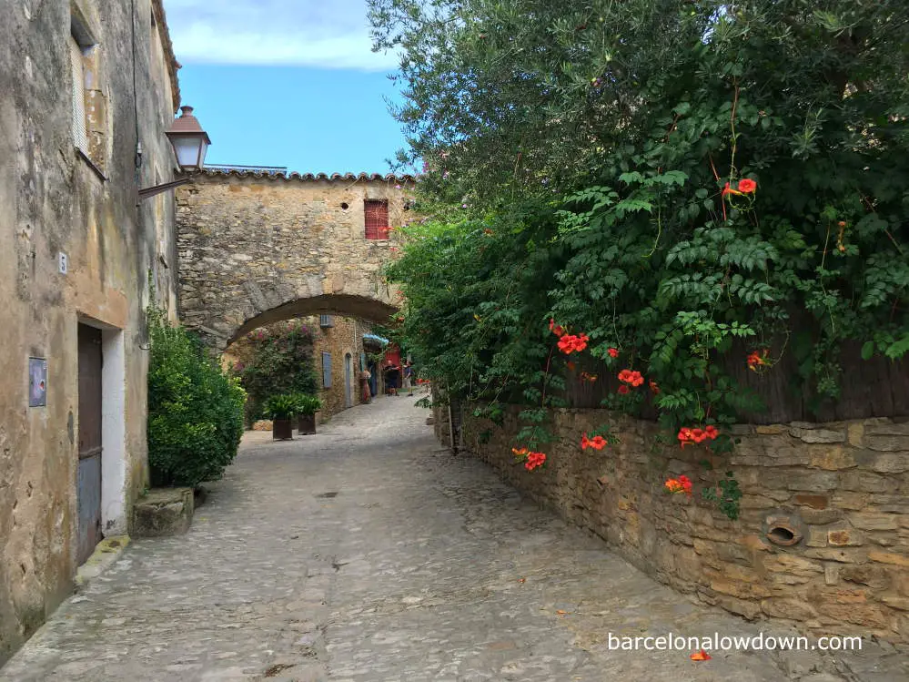 A medieval archway and orange flowers in Peratallada, Spain