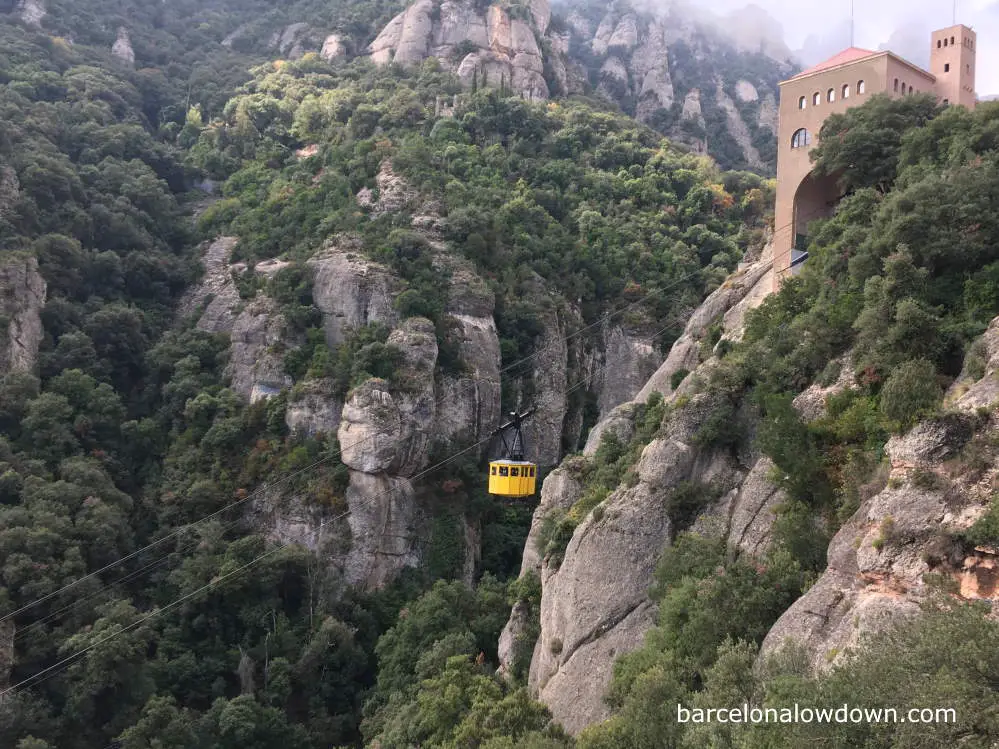 A yellow cable car going up a mountain in Spain