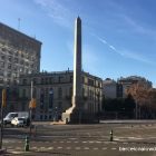 A tall granite obelisk in Barcelona bathed in early morning sunshine