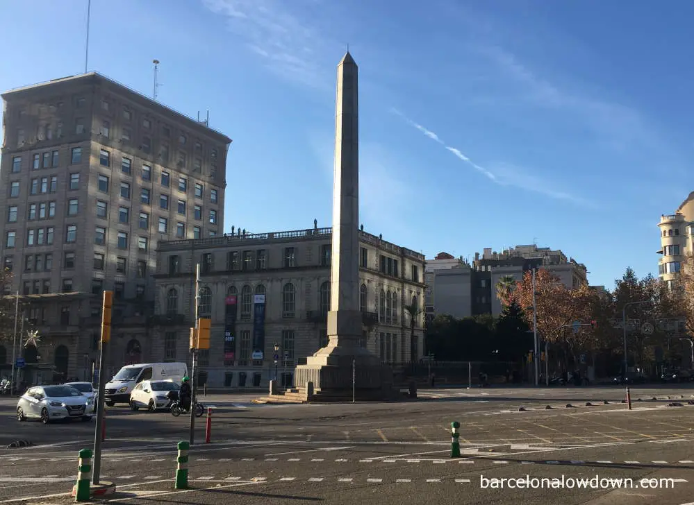 A tall granite obelisk in Barcelona bathed in early morning sunshine