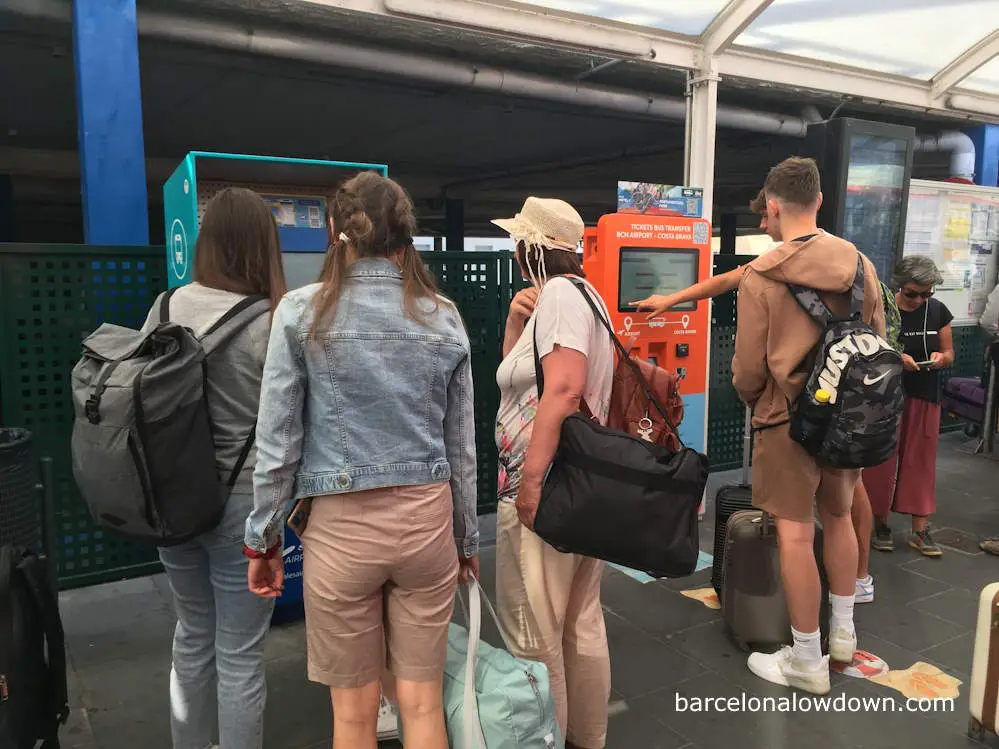 A queue of people beside the intercity bus ticket machines at Barcelona airport Terminal 2