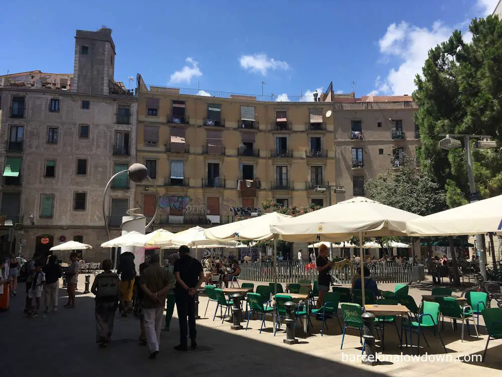 People walking through Plaça de George Orwell, a run down square in Barcelona's Gothic Quarter