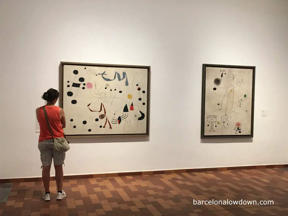 A woman admiring paintings by Joan Miró