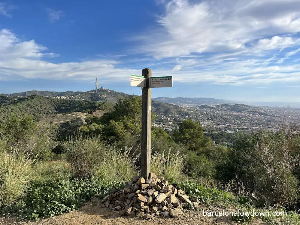 Wooden signpost on the PR-C 171 trail in Barcelona you can see the church on Tibidabo and the city of Barcelona in the background