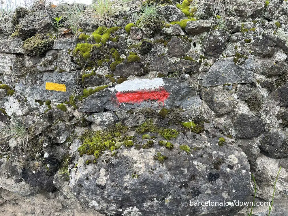 White and red trail GR markers painted on a stone wall
